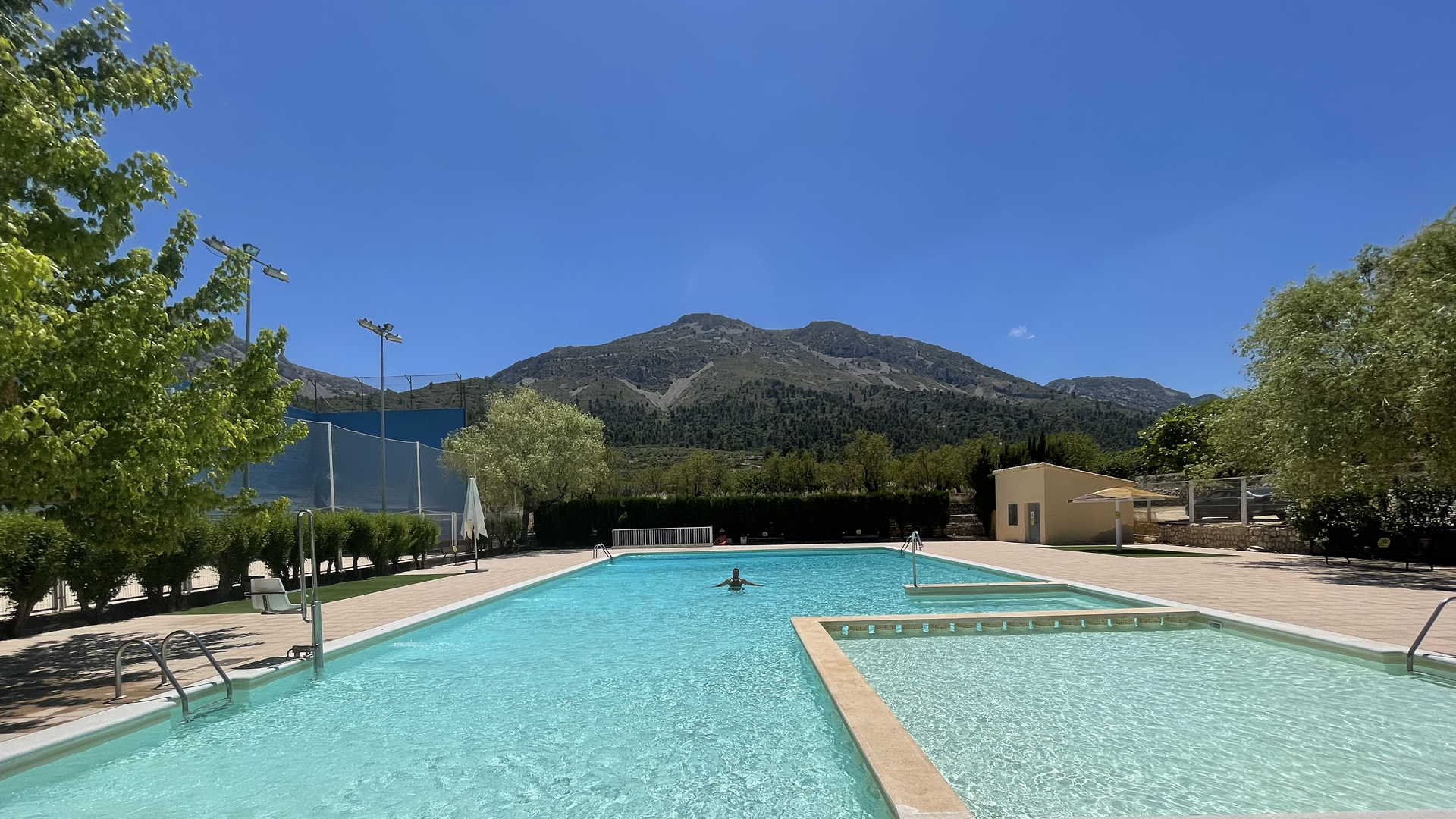 piscina municipal de Fageca con el frontón municipal al lado y la Serrella al fondo.